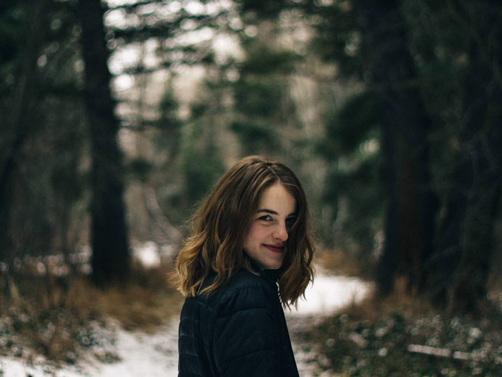 Garota posando para foto em uma floresta com fundo desfocado - Dicas para tirar fotos melhores nas suas viagens