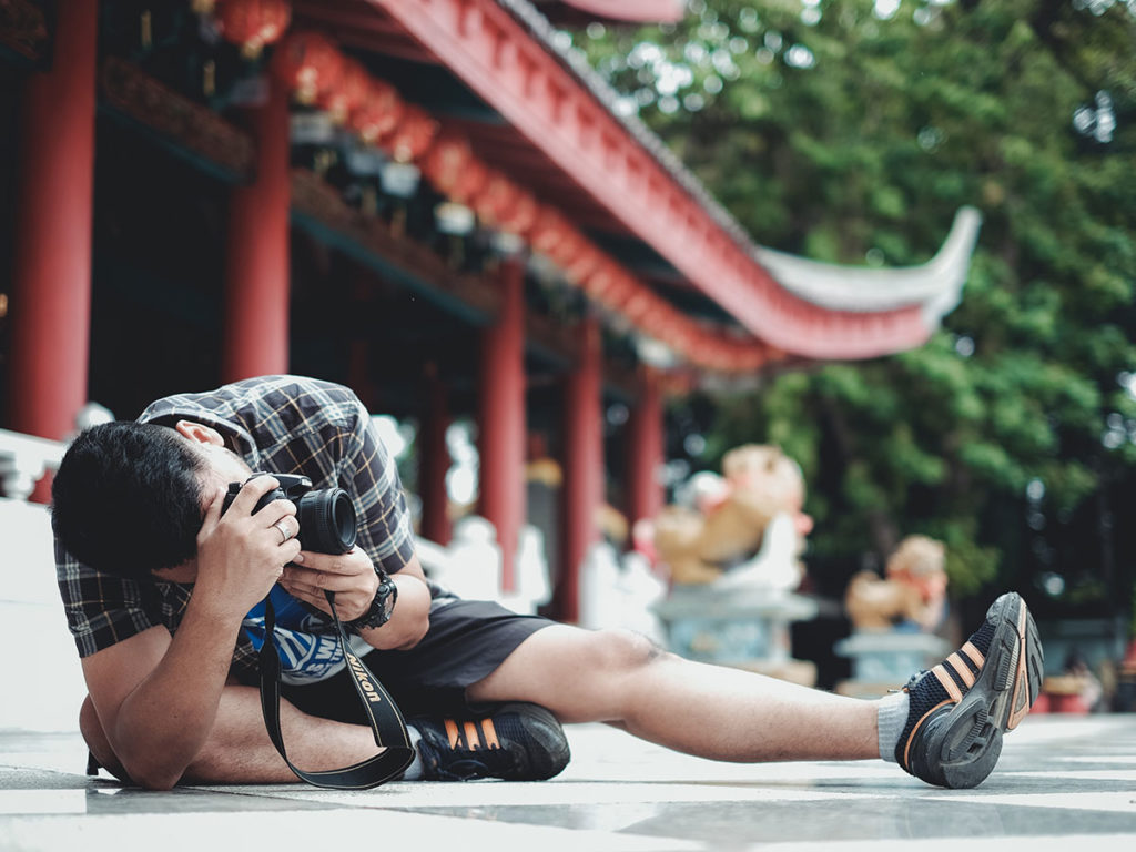 Homem fotografando sentado no chão em busca do melhor ângulo