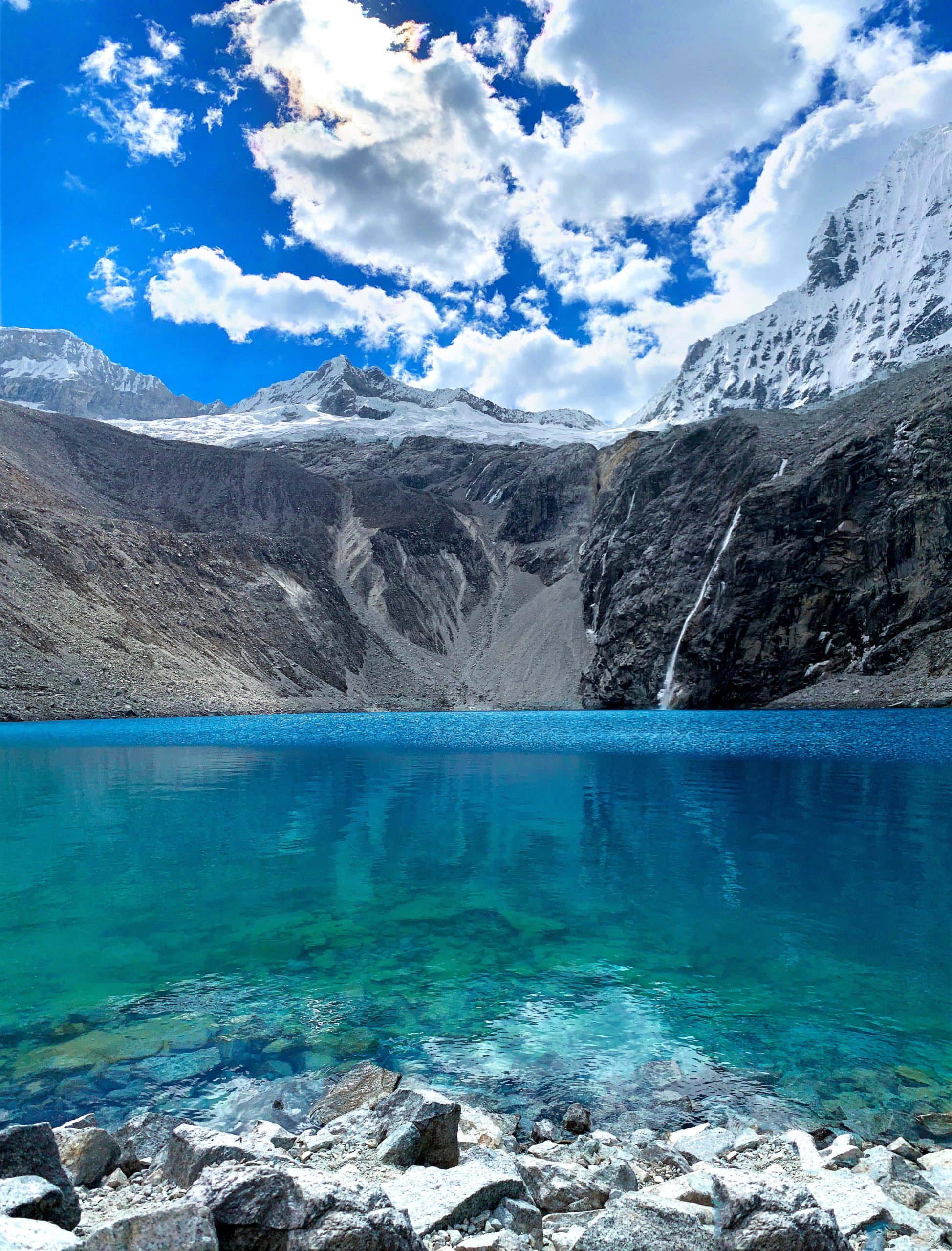 Água cristalina em meio às montanhas com neve na Laguna 69 - O que fazer no Peru